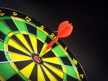 Dart hitting a bulls-eye on dartboard to show excellence